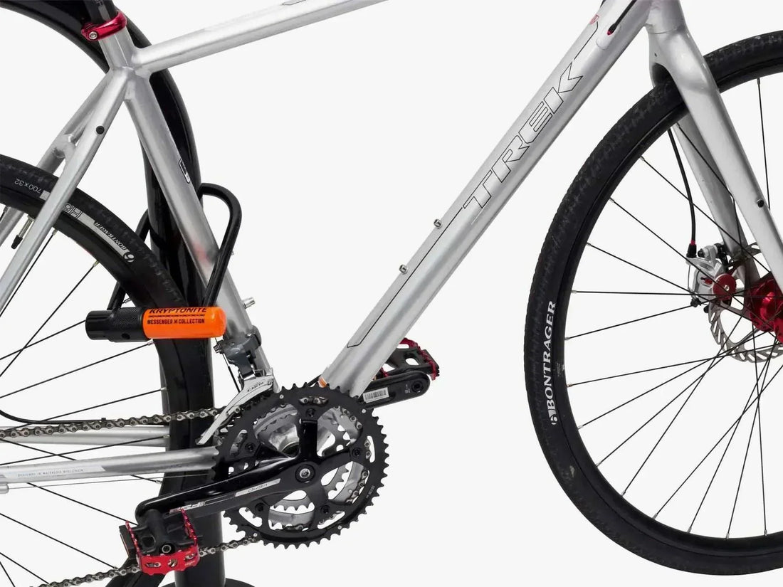 Silver Trek electric bike side view with Kryptonite U-lock securing frame and rear wheel