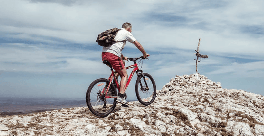 Electric mountain bike with rider climbing rocky hill in outdoor trail setting, side view