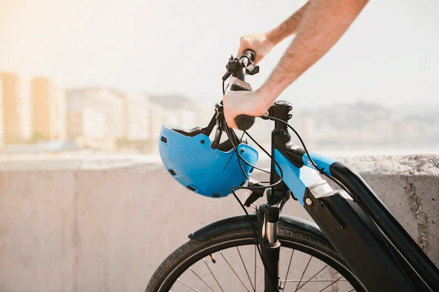 Electric bike black frame front view with blue helmet outdoors on urban path