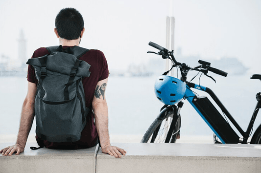 Electric bike with blue frame and helmet, side view, near waterfront with person sitting