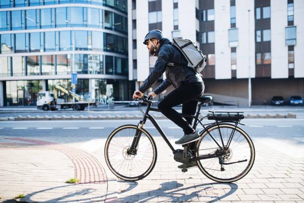 Electric bike with rear battery side view, man commuting in city with helmet and backpack