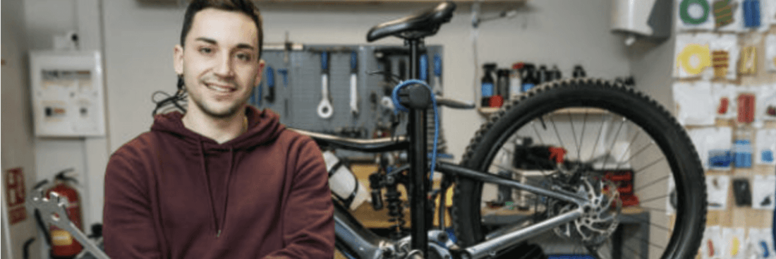 Electric mountain bike on repair stand with mechanic in workshop, side view