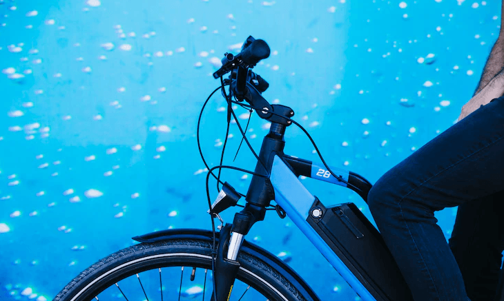Electric bike with integrated battery, blue frame, side view, rider on city street
