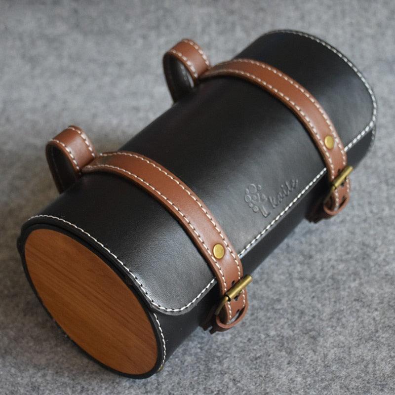 Handmade black leather bicycle saddle bag with brown straps and stitching, featuring a rainproof design, placed on a grey surface – Pogo Cycles